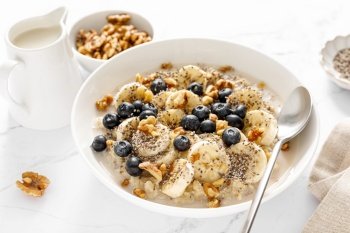 Oatmeal bowl. Oat porridge with banana, blueberry, walnut, chia seeds and oat milk for healthy breakfast. Healthy diet food