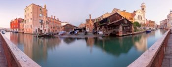 Facades of old traditional medieval houses along the canal at sunrise. Venice. Italy.. Venice. Old colorful houses over the canal in the early morning.