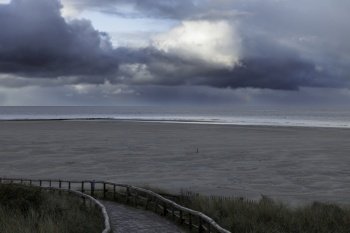 the beach of Texel with the horizon in the background and thick dark rain clouds above the beach