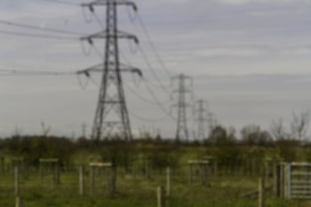 Blurred Line of electric pylons into distance above countryside, landscape