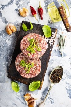 Billets for burgers from fresh minced meat with spices on a wooden board