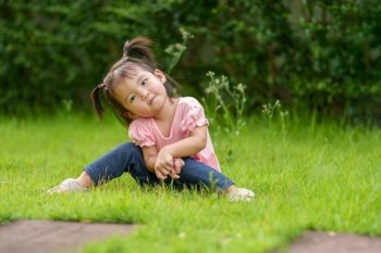 happy toddler girl sitting in grass field
