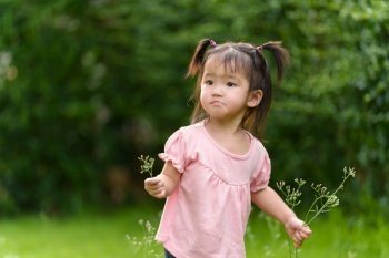toddler girl playing grass flower in a field