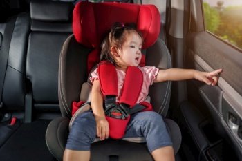 toddler girl sitting in a car seat and looking out of the window
