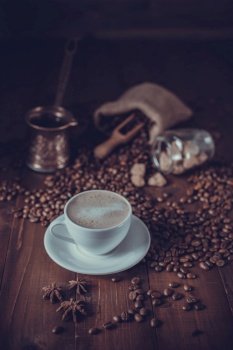 Cup of coffee and milk with beans on wooden table. Homemade coffee at table background