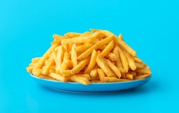 Plate with homemade french fries, minimalist on a blue table. Close-up with delicious fried potatoes on a plate.