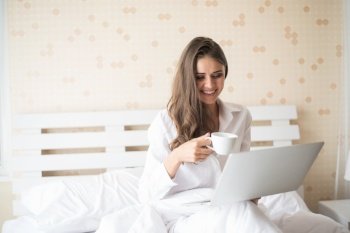 Happy Beautiful woman working on a laptop on the bed in the house