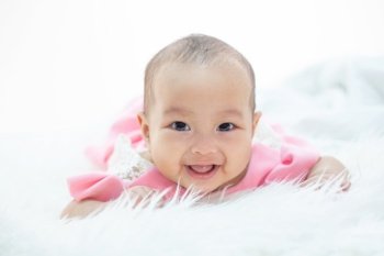 happy baby lying on white bed
