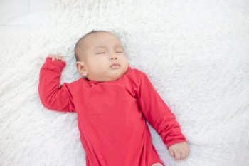 Babies wearing red shirts sleeping in bed