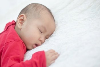 Babies wearing red shirts sleeping in bed