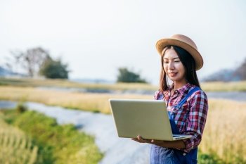 Smart Woman farmer looking barley field with laptop computer