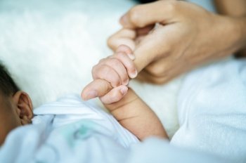 Newborn baby holding hands mom