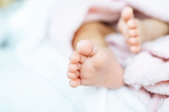 Newborn baby feet on a white blanket.