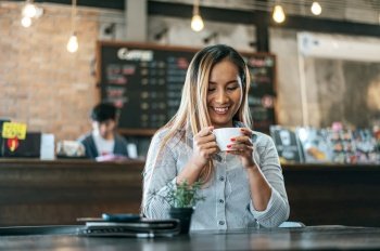 woman sitting happily drinking coffee in cafe shop