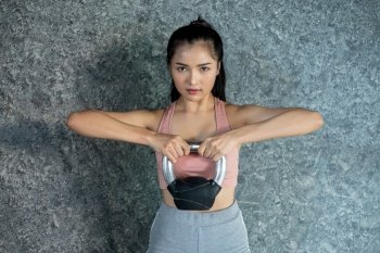 Asian girls are exercising with the Kettlebell in the gym.