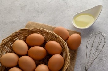 Selective focus eggs on sack cloth, many eggs on wicker basket and glasses bowl, oil and egg whisk placed on the floor, preparing for cooking food or dessert, copy 
space
