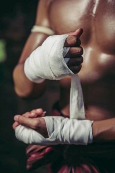 The boxer sat on the stone, tied the tape around his hand, preparing to fight.