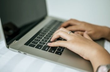 A woman’s hand that is placed on a laptop. Selective focus.