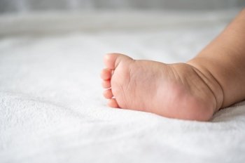 Baby feet in white bed. Selective focus.