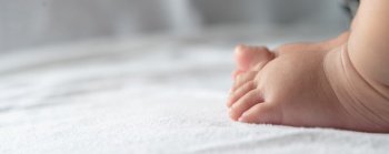Baby feet in white bed. Selective focus.
