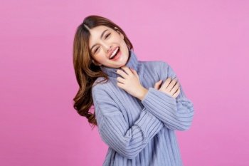 Portrait of Smiling young woman sweet winsome lovely attractive charming cheerful cheery lady hugging herself isolated over pink background. People lifestyle and expression concept.