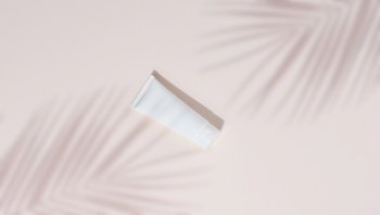 White plastic tubesfor cosmetics on a beige background, top view. Template for branding, advertising and product promotion