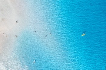 Aerial view of amazing sea coast. Top view from drone of beach with white sand, swimming people in blue transparent water at sunny day. Summer in La Pelosa beach, Sardinia, Italy. Tropical landscape