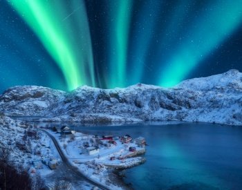 Polar lights over the snowy mountains, sea at night in Lofoten, Norway. Aerial view of aurora borealis, rocks in snow. Winter landscape with northern lights and fjord. Starry sky with aurora. Top view