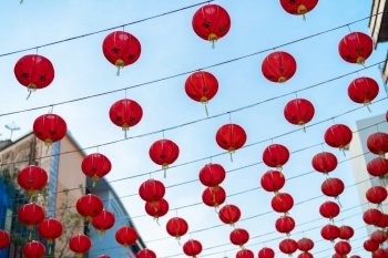 Red chinese lanterns hanging on wire outdoor lamps in temple of China Town decoration on Chinese New Year festival culture with blue sky at night background in Asia.
