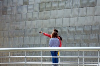 tourists taking a selfie, visiting Bilbao city, Basque country, Spain