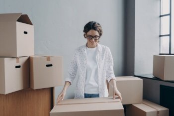Happy businesswoman packing parcels of her online store, smiling woman looking at cardboard box, satisfied female businessperson preparing orders for sending. Small business, startup concept.. Happy businesswoman packing parcel preparing online store orders for sending. Small business concept