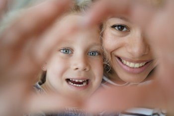 Little daughter, mother showing heart gesture, symbol love care support. Smiling mom and adopted preschooler child girl takes selfie, looking at camera together, show sign of gratitude. Happy adoption. Adopted daughter, mom showing heart gesture together, symbol of love, care, support. Happy adoption