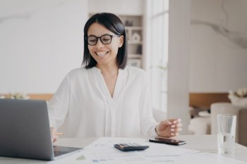 Happy female employee working at laptop got email with good news. Smiling businesswoman in glasses, looking at computer screen celebrates job promotion, successful deal, sitting at office desk.. Happy female employee working at laptop got email with good news. Job promotion, successful deal