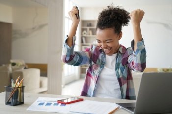 Excited african american teen girl received good news email on laptop, biracial high schoolgirl got good exam scores, clenching her fists making yes gesture celebrates win, personal success.. Excited african american teen girl received good news email on laptop screams, makes yes gesture