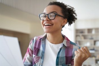 Excited african american teen girl in glasses feels happiness, received good news. Biracial female student celebrate victory, enjoy success, personal achievement, got student scholarship.. Excited african american teen girl in glasses celebrate victory, enjoy success, personal achievement
