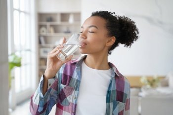 African american woman enjoy drinking pure crystal filtered potable water. Thirsty female with eyes closed swallow mineral aqua from glass at home kitchen. Thirst, healthy lifestyle, body care concept. African american young girl enjoy drinking pure filtered water from glass at home. Healthy lifestyle