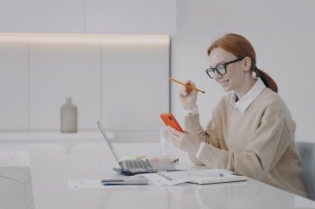 Lazy young woman is texting at workplace in office. Employee is sending messages sitting at her desk. Manager in glasses and forman wear surfing internet, having fun. Being distracted at work concept.. Lazy young woman is texting at workplace. Employee is distracting, surfing internet and having fun.