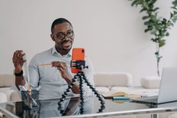 African american businessperson, executive leader giving presentation for team online by video call using smartphone. Black male business coach teaching marketing. E-learning, distance education. African american businessperson gives presentation for team online by video call using smartphone
