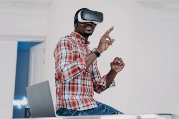 Interactive virtual reality goggles. African student in vr glasses at home office. Freelancer is working on design project. Digital technology for business and e-learning. Virtual distant study.. Interactive virtual reality goggles. African student in vr glasses at home office.