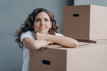Face of young lady dreaming while sitting on floor in new apartment or house. Happy attractive spanish woman packing boxes going to move. Concept of future and perspective.. Face of young spanish lady which is dreaming while sitting on floor in new apartment or house.
