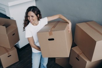Excited spanish woman renting home. Boxes unpacking in new house. Lady is unloading cardboard boxes in room of apartment. Changes, improvement and new life concept.. Excited spanish woman renting home. Boxes unpacking in new house. Changes and improvement concept.