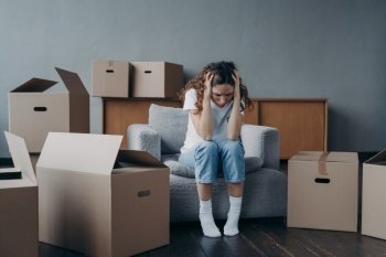 Tired european woman sitting among packed boxes. Girl is upset with moving. Hopeless young lady in jeans and white t-shirt getting in trouble. Depression and bankruptcy concept.. Tired european woman sitting among packed boxes. Hopeless young lady getting in trouble
