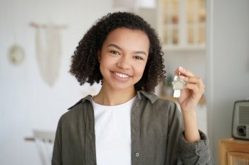 Smiling mixed race teen girl proudly holds keys to her new home as a tenant or homeowner, embarking on her rental housing or mortgage journey.