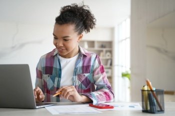 Mixed race teen girl student engages in distance education, focused on her laptop screen as she learns and studies from home.