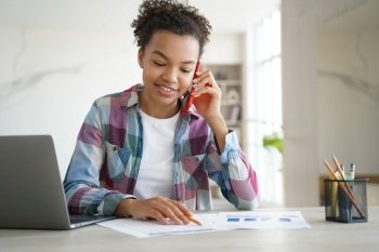 Mixed race teen girl school student engages in a phone call, discussing homework with a friend while sitting at her desk.