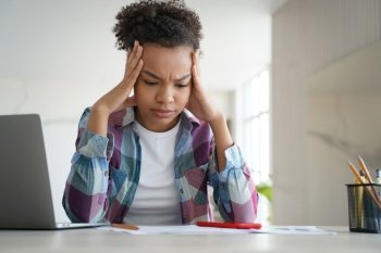 Biracial teen girl school student feels stressed while doing homework on her laptop, facing challenges of difficult e-learning.
