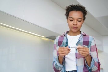 Mixed race teen girl checks body temperature at home using a digital thermometer, ensuring her health and well-being.