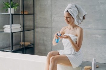 Woman applies natural skincare in modern bathroom. Body care treatment after shower.