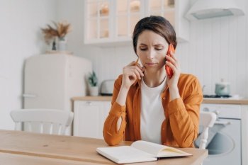 Nervous woman calls customer service, has unpleasant conversation at kitchen table. Freelancer businesswoman discusses project while working from home