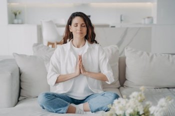 Spanish woman relaxes in lotus pose at home. Yoga, meditation, stress reduction
